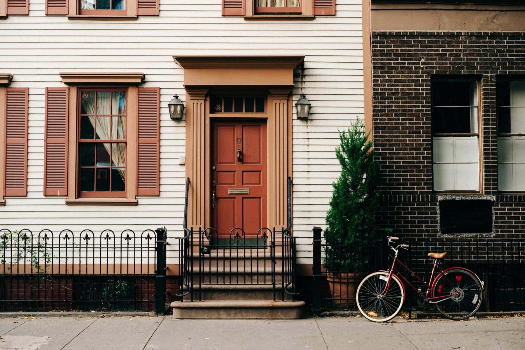 Historic Newburgh-style brick rowhouse with shuttered windows and red door
